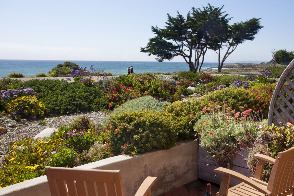 A garden with flowers and chairs overlooking the sea