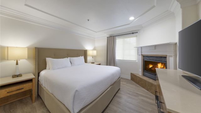 A well-appointed guest room with a large bed, fireplace, and flat-screen TV.